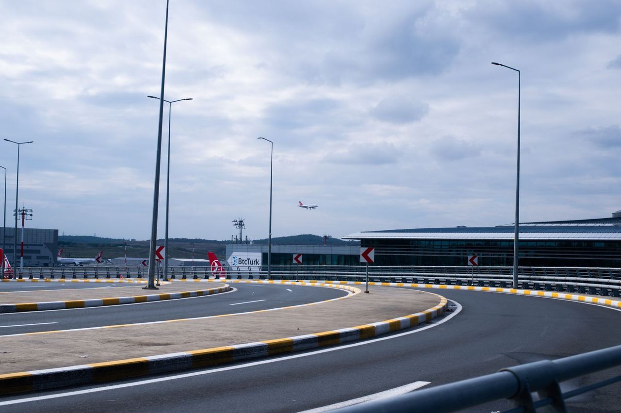 Illustrative photo: airport approach road with a landing plane